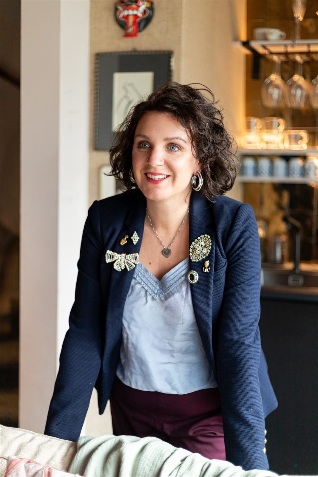 Elianne Alblas, lachend in een donkerblauwe blazer in een sfeervol horeca-interieur